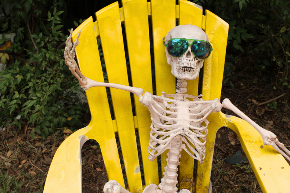 A picture of a skeleton in a yellow chair enjoying the summertime.